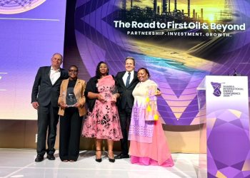 WhatsApp Image 2026-04-16 at 110904 AM | Mining and Energy Namibia | Namibia’s Leading Mining & Energy News Five people stand on a stage posing with a glass trophy at the Namibia International Energy Conference 2026, with a purple backdrop reading 'The Road to First Oil & Beyond.'