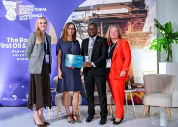 Group of four professionals on stage at the Namibia International Energy Conference 2026, with a blue backdrop and an award plaque held by the center-right man.
