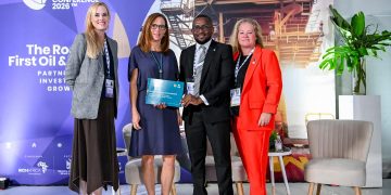 Group of four professionals on stage at the Namibia International Energy Conference 2026, with a blue backdrop and an award plaque held by the center-right man.