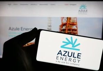 Close-up of a hand holding a white card with the Azule Energy logo in blue, blurred Azule Energy website on a screen in the background.