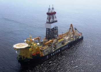 Offshore drilling vessel with a tall derrick and complex equipment on the deck, sailing in open ocean, labeled SAIPEM 12000 on the hull