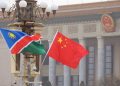 Namibia and China flags waving in front of a government building with columns, signaling international presence.