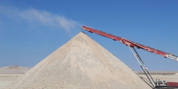 gypsum | Mining and Energy Namibia | Namibia’s Leading Mining & Energy News Large mound of light gravel or sand in a desert, with a red conveyor belt depositing material atop the pile.
