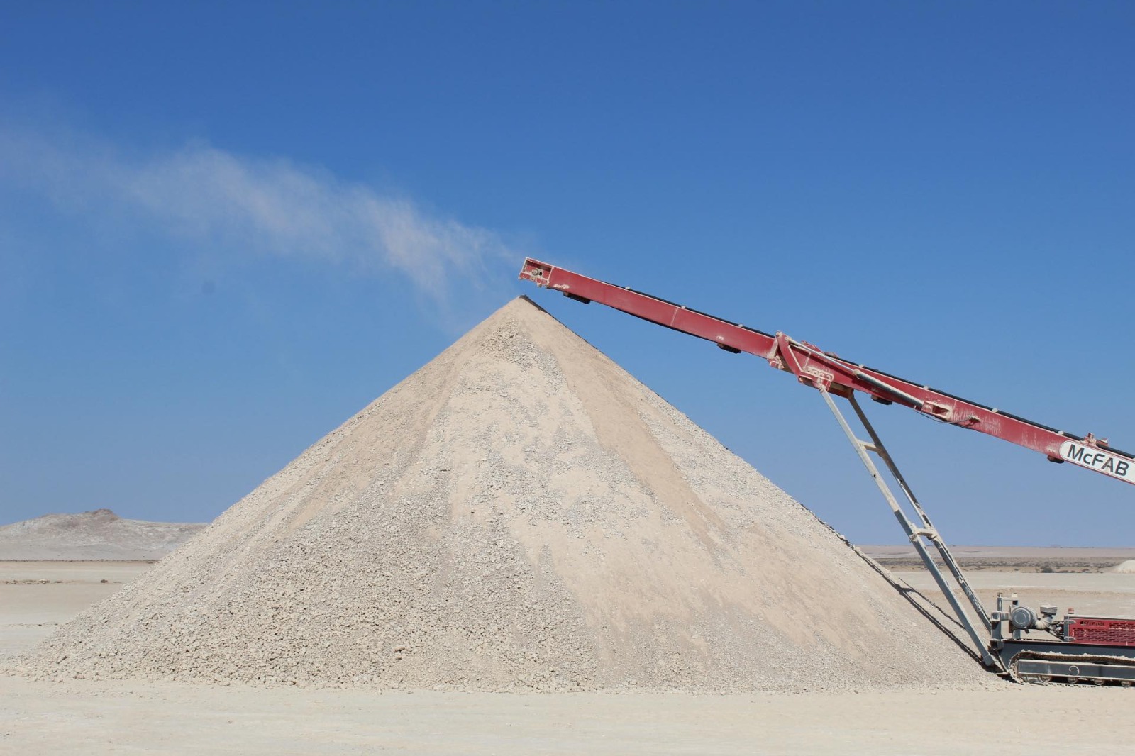 gypsum | Mining and Energy Namibia | Namibia’s Leading Mining & Energy News Large mound of light gravel or sand in a desert, with a red conveyor belt depositing material atop the pile.