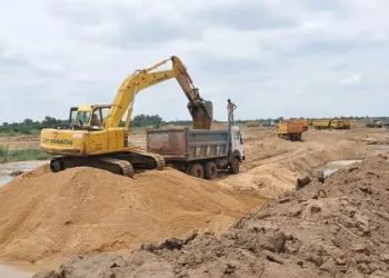 sand mining | Mining and Energy Namibia | Namibia’s Leading Mining & Energy News Yellow excavator loading sand into a dump truck at a dirt construction site, with more equipment lined up in the distance