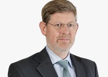Portrait of a middle-aged man with glasses, gray beard, wearing a dark suit and light blue shirt with a teal tie, looking at the camera.