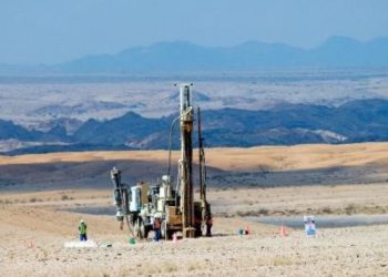 critical metals 7 | Mining and Energy Namibia | Namibia’s Leading Mining & Energy News Oil drilling rig in a barren desert, workers in hi-vis near machinery with mountains in the distance.