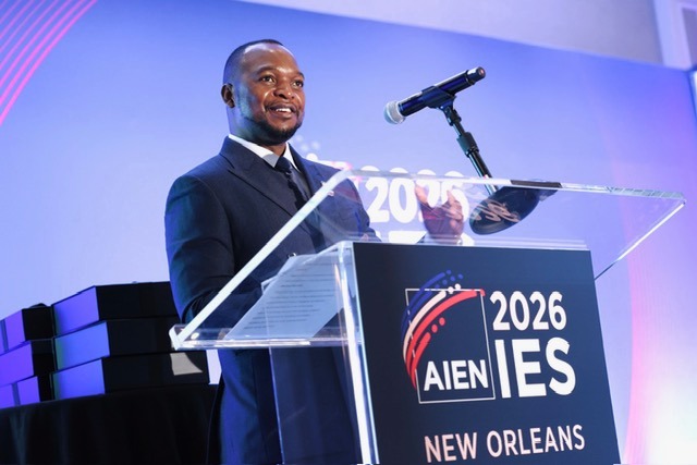 WhatsApp Image 2026-06-17 at 124827 PM | Mining and Energy Namibia | Namibia’s Leading Mining & Energy News Male presenter in a suit speaks at a clear podium on a lit stage; sign reads '2026 IES' and 'New Orleans' in the foreground.