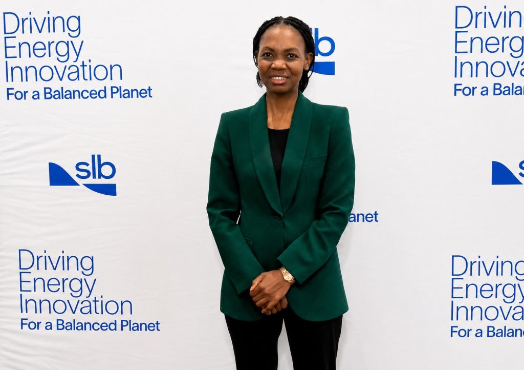 AUNE AMUTENYA | Mining and Energy Namibia | Namibia’s Leading Mining & Energy News Professional woman in a dark green blazer posing in front of a white backdrop with 'Driving Energy Innovation' slogan and SLB logos.
