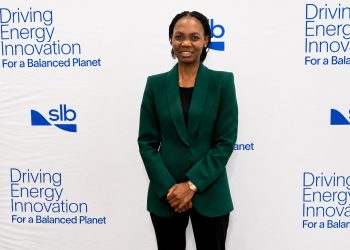 AUNE AMUTENYA | Mining and Energy Namibia | Namibia’s Leading Mining & Energy News Professional woman in a dark green blazer posing in front of a white backdrop with 'Driving Energy Innovation' slogan and SLB logos.