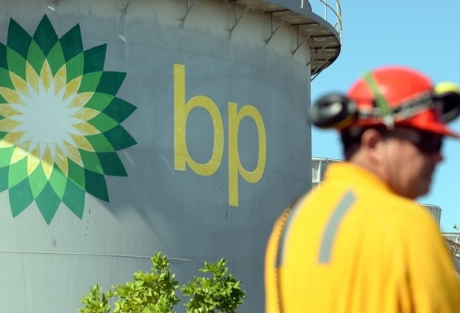 ECO | Mining and Energy Namibia | Namibia’s Leading Mining & Energy News BP logo on a large cylindrical storage tank with a worker in yellow safety gear in the foreground against a blue sky.