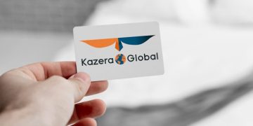 Close-up of a hand holding a white business card displaying the Kazera Global logo (orange and blue wings with a globe) and text