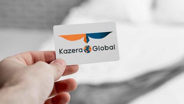 Close-up of a hand holding a white business card displaying the Kazera Global logo (orange and blue wings with a globe) and text