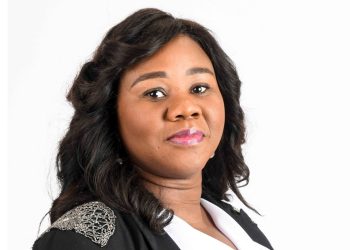 Professional headshot of a Black woman with shoulder-length wavy hair, wearing a black blazer with silver embroidery, smiling slightly.