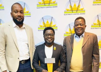 WhatsApp Image 2026-07-07 at 45407 PM | Mining and Energy Namibia | Namibia’s Leading Mining & Energy News Three men in suits pose for a photo at an Electricity Control Board event, the center man holding a yellow trophy in front of branded backdrop.