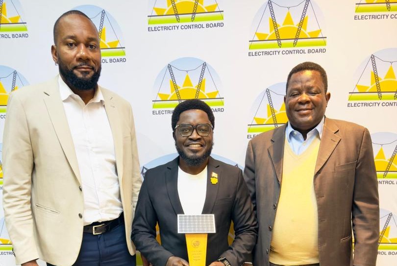 WhatsApp Image 2026-07-07 at 45407 PM | Mining and Energy Namibia | Namibia’s Leading Mining & Energy News Three men in suits pose for a photo at an Electricity Control Board event, the center man holding a yellow trophy in front of branded backdrop.