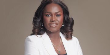 Saave Nakashole | Mining and Energy Namibia | Namibia’s Leading Mining & Energy News Professional portrait of a Black woman with shoulder-length curls, wearing a white blazer and jewelry, against a neutral background.
