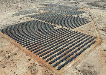 anirep | Mining and Energy Namibia | Namibia’s Leading Mining & Energy News A large solar farm with rows of dark solar panels in a desert landscape from an aerial view.