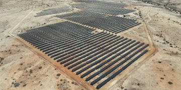 anirep | Mining and Energy Namibia | Namibia’s Leading Mining & Energy News A large solar farm with rows of dark solar panels in a desert landscape from an aerial view.