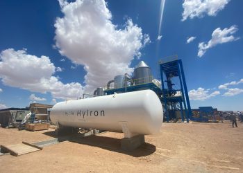 Large white industrial tank labeled H2Fe HYIRON at a desert facility with blue sky and metal structures nearby