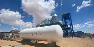 Large white industrial tank labeled H2Fe HYIRON at a desert facility with blue sky and metal structures nearby