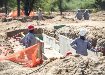 WhatsApp Image 2026-07-20 at 41357 PM | Mining and Energy Namibia | Namibia’s Leading Mining & Energy News Construction workers wearing hard hats stand beside a dug trench with concrete forms on a sunny construction site.