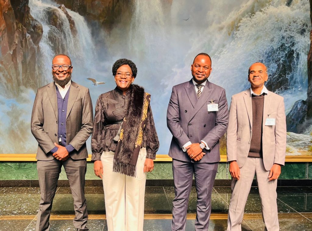 WhatsApp Image 2026-07-21 at 43514 PM | Mining and Energy Namibia | Namibia’s Leading Mining & Energy News Four professionally dressed people stand in a row, smiling, in front of a waterfall backdrop.