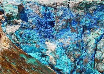 Close-up of a rugged rock surface with vibrant blue and teal mineral colors, likely copper minerals like azurite.