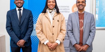 Three professionally dressed people posing side by side in front of blue/white banners with logos (Hanns Seidel Foundation and Economic Association of Namibia).