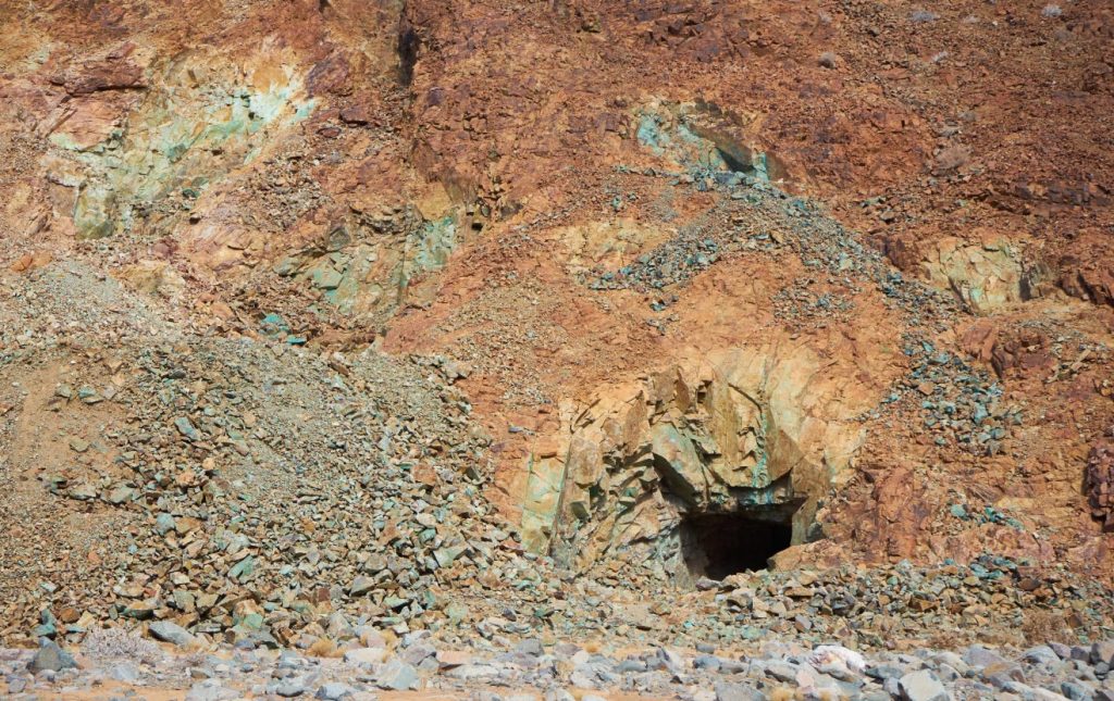 COPPER01 | Mining and Energy Namibia | Namibia’s Leading Mining & Energy News Rugged hillside of orange-brown rock with a dark mine entrance at center-right, surrounded by loose stones and rubble