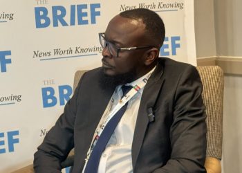 Man in a dark suit and glasses seated in a discussion, with a backdrop that says 'THE BRIEF' and 'News Worth Knowing'.
