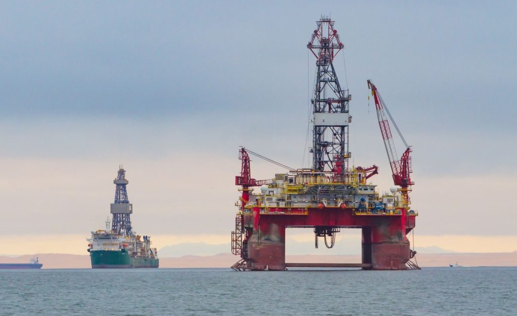 WhatsApp Image 2026-08-20 at 63154 PM | Mining and Energy Namibia | Namibia’s Leading Mining & Energy News Large offshore oil platform with a tall derrick and cranes in calm sea; a second platform and a ship visible in the distance.