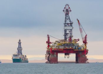 WhatsApp Image 2026-08-20 at 63154 PM | Mining and Energy Namibia | Namibia’s Leading Mining & Energy News Large offshore oil platform with a tall derrick and cranes in calm sea; a second platform and a ship visible in the distance.