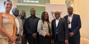 WhatsApp Image 2026-08-21 at 112425 AM | Mining and Energy Namibia | Namibia’s Leading Mining & Energy News Six professionals posing for a group photo indoors, wearing business attire, with a banner in the background featuring a crest/logo.