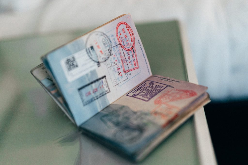 VISA | Mining and Energy Namibia | Namibia’s Leading Mining & Energy News Open passport showing multiple stamps and visas on a desk surface, with pages fanned out.