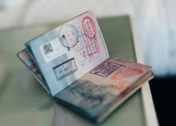 VISA | Mining and Energy Namibia | Namibia’s Leading Mining & Energy News Open passport showing multiple stamps and visas on a desk surface, with pages fanned out.