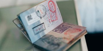 VISA | Mining and Energy Namibia | Namibia’s Leading Mining & Energy News Open passport showing multiple stamps and visas on a desk surface, with pages fanned out.