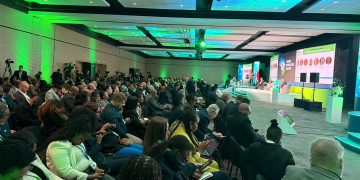 WhatsApp Image 2026-09-15 at 33950 PM | Mining and Energy Namibia | Namibia’s Leading Mining & Energy News Large conference hall with green lighting, audience seated facing a panel on stage with microphones and screens in the background.