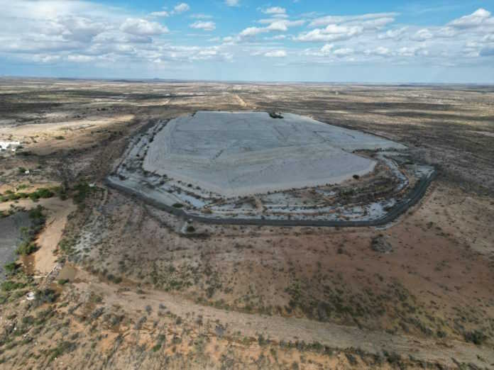 UNICORN RESOURCES | Mining and Energy Namibia | Namibia’s Leading Mining & Energy News Aerial view of a large, flat, light-gray concrete pad encircled by a road in a dry desert landscape.