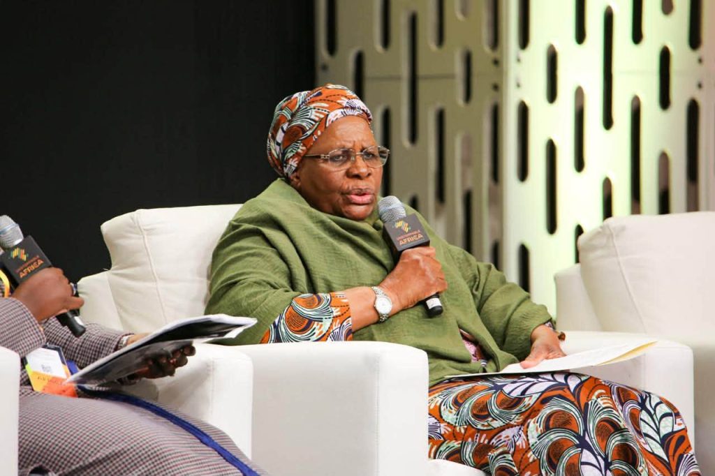WhatsApp Image 2026-09-21 at 85422 PM | Mining and Energy Namibia | Namibia’s Leading Mining & Energy News Panelist in a green shawl and colorful headwrap speaks into a handheld microphone, holding papers.