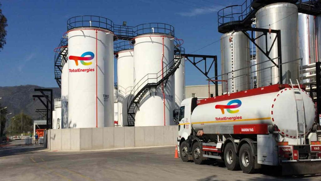 TOTALENERGIES9 | Mining and Energy Namibia | Namibia’s Leading Mining & Energy News Industrial facility with tall white TotalEnergies storage tanks and a branded tanker truck in the foreground under a blue sky with stairs and piping visible.
