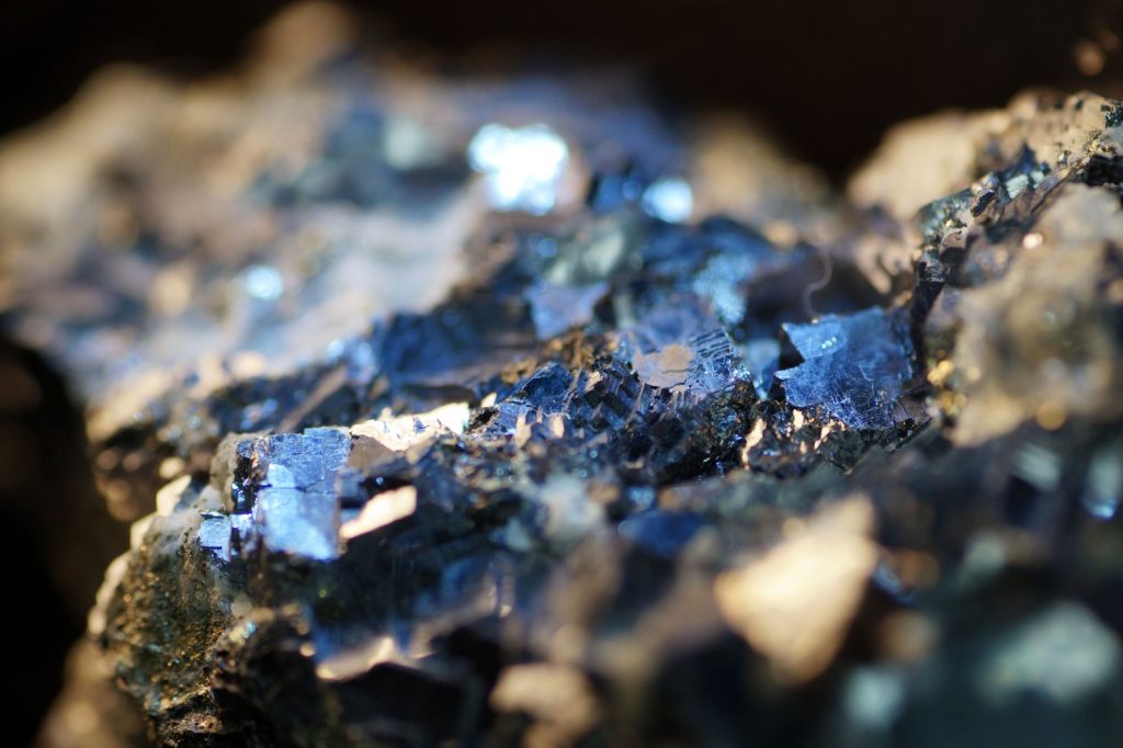 CRITICAL MINERALS | Mining and Energy Namibia | Namibia’s Leading Mining & Energy News Close-up of blue crystalline minerals embedded in a rocky matrix, sparkling under light.