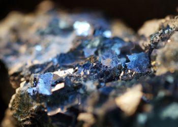 Close-up of blue crystalline minerals embedded in a rocky matrix, sparkling under light.