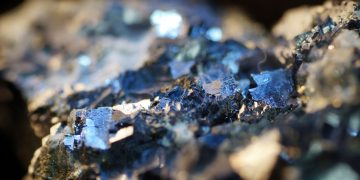 Close-up of blue crystalline minerals embedded in a rocky matrix, sparkling under light.