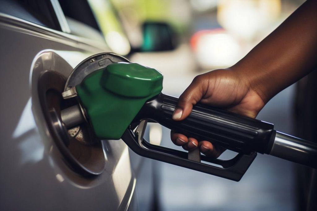 FUEL | Mining and Energy Namibia | Namibia’s Leading Mining & Energy News Close-up of a green gas pump nozzle fueling a car's fuel inlet with a person's hand on the nozzle grip.