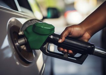 FUEL | Mining and Energy Namibia | Namibia’s Leading Mining & Energy News Close-up of a green gas pump nozzle fueling a car's fuel inlet with a person's hand on the nozzle grip.