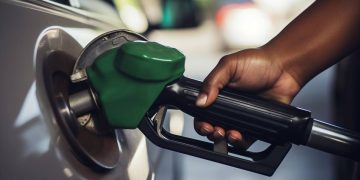 FUEL | Mining and Energy Namibia | Namibia’s Leading Mining & Energy News Close-up of a green gas pump nozzle fueling a car's fuel inlet with a person's hand on the nozzle grip.