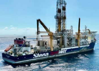 Offshore drilling ship at sea, blue hull with 'Stena Drilling' branding and tall yellow derricks towering above.