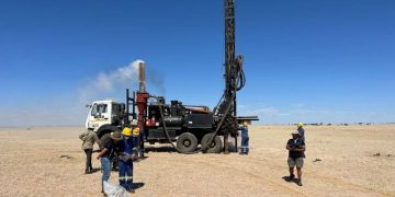 Elevate-Uranium-ASX-EL8-increases-drilling-operation-Koppies-project-Namibia-Africa | Mining and Energy Namibia | Namibia’s Leading Mining & Energy News Mobile drilling rig mounted on a truck in a flat desert, workers in hard hats and coveralls nearby.