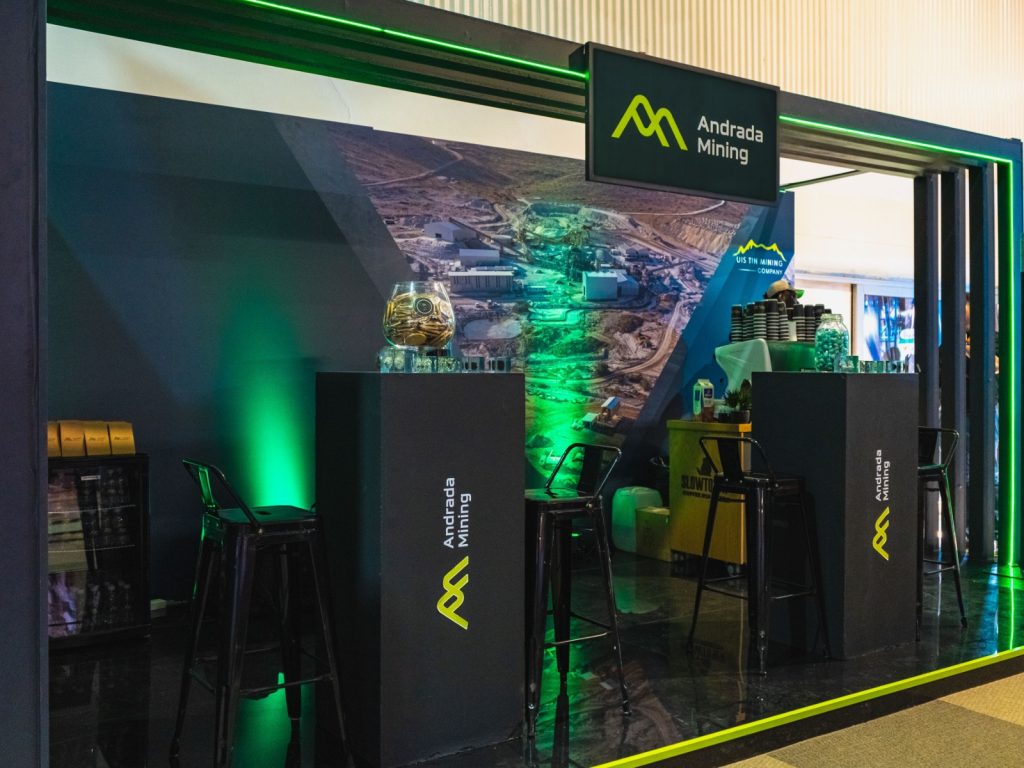 WhatsApp Image 2026-10-23 at 173925 | Mining and Energy Namibia | Namibia’s Leading Mining & Energy News Andrada Mining booth with black podiums, lime logo, green lighting, and a large mining backdrop.
